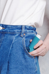 Woman puts an inhaler in pocket to treat asthma. World Asthma Day. Concept of allergy care