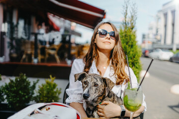 Dog with a young woman in a cafe restaurant on the terrace, dog friendly food establishments.