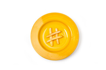 Patatas fritas sobre un plato redondo amarillo formando el símbolo de hastag sobre un fondo blanco...