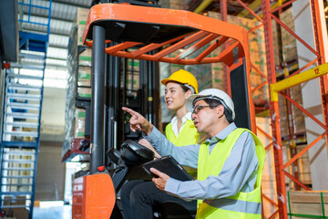 workers team meeting and training working at warehouse.Manager asian man standing with pointing check order with tablet.Female asia worker at large Warehouse in forklift loader - obrazy, fototapety, plakaty