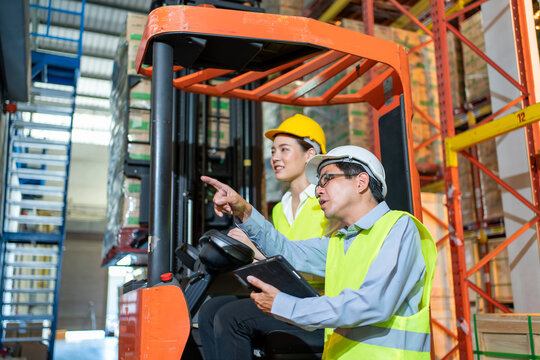 workers team meeting and training working at warehouse.Manager asian man standing with pointing check order with tablet.Female asia worker at large Warehouse in forklift loader