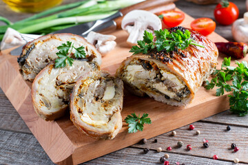 Roasted pork roll stuffed mushrooms and cheese on a board