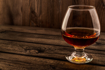 Glass of brandy and on an old wooden table. Angle view