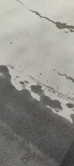 Gray black abstraction on the asphalt. Partially wet, partially dried asphalt will create an...