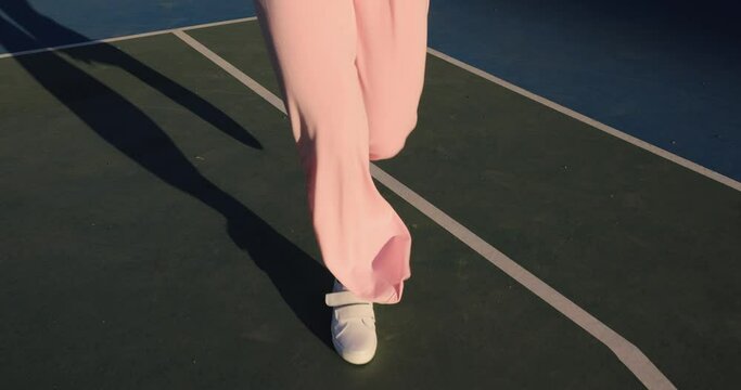Creative fashion video female legs in pink pants running on a stadium, slow motion
