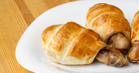 Appetizing chicken leg in puff pastry on a white plate with copy space