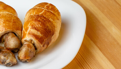 Appetizing chicken leg in puff pastry on a white plate with copy space