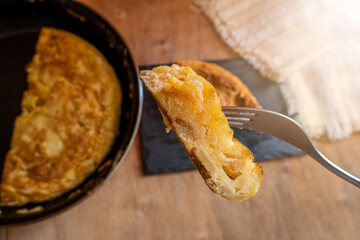 Spanish omelette, homemade recipe, on a wooden board and a black slate plate.
