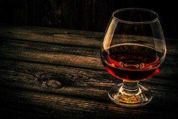 Glass of brandy and on an old wooden table. Angle view