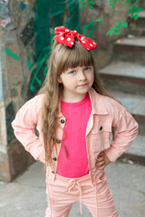 A little girl with long hair stands with her hands at her waist