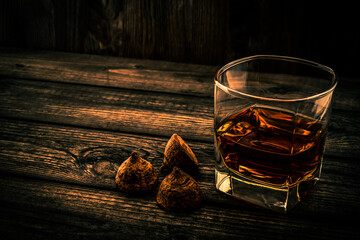 Glass of brandy and a chocolate truffles on an old wooden table. Angle view