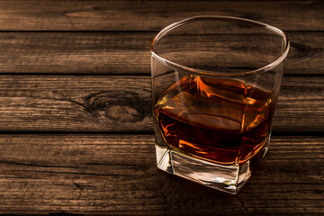 Glass of brandy and on an old wooden table. Close up view