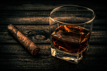 Glass of brandy and cuban cigar on an old wooden table. Close up view