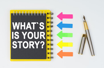 On a white background lies a pen, arrows and a notebook with the inscription - WHATS IS YOUR STORY