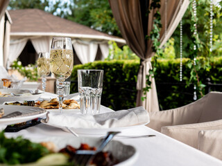 Glasses of champagne on a set table in an open-air restaurant.