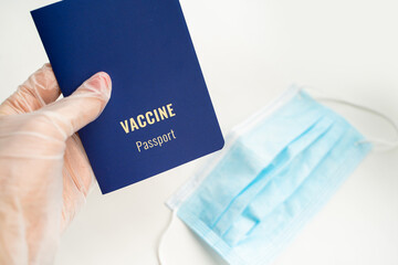 Vaccine passport control. Hand in glove holding blue immune certificate. Face mask on background. Pandemic covid documents new rules theme. Horizontal photo © Iryna&Maya