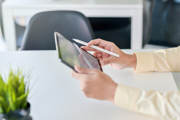 Close up of a businessman hand holding a pen with a tablet at the office.