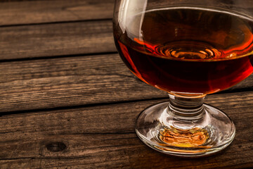 Glass of brandy on an old wooden table. Close up view