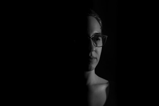 A young middle-aged woman with ambition and looking to the future. Low-key photography portrait with half of her face visible.