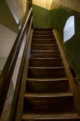 An old wooden staircase, steps and railings, light from a side window. © Anelo