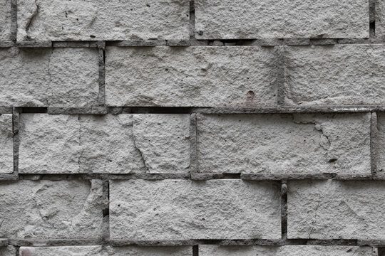 The background is the texture of a shattered corrosion-prone crumbling brick wall made of white gray brick. Abandoned brick wall dilapidated with time removed close-up. High quality photo
