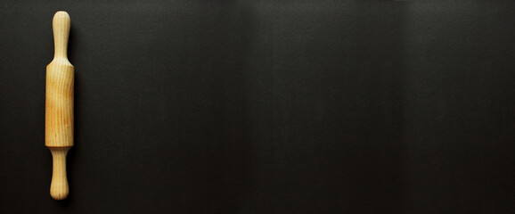 A rock for a test made of wood on a black background. Cooking and baking. cookery. View from above. Copy space. The scayth for the test is crushed on the left straight.