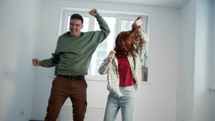 Heterosexual couple rejoices dancing in new home