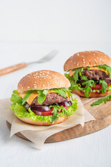 Two juicy burgers made of grilled ground beef meat, cheese, lettuce, onion rings and tomatoes...