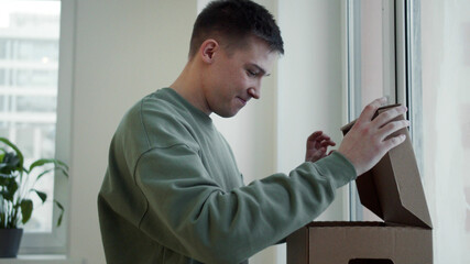 Fototapeta premium The student puts the box on the windowsill and takes the books out of it