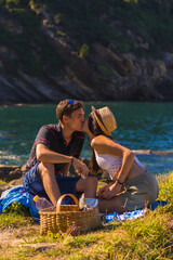 Romantic scene of a couple kissing on the picnic in the mountains by the sea enjoying the heat, summer lifestyle