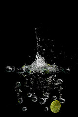bright juicy fruits with splashes fly into the aquarium on a black background