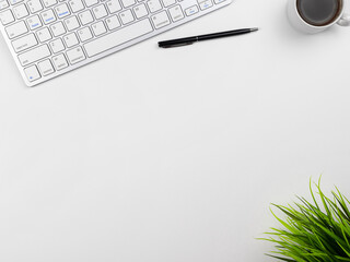 Office place in the workplace. Top view of white office desktop with keyboard, coffee mug and office flower. Copy space for your text. Business, growth and modern work concept