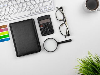 Office place in the workplace. Top view of white office desktop with keyboard, coffee mug and office flower. Copy space for your text. Business, growth and modern work concept
