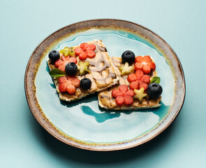 Delicious diet breakfast cereal sandwiches with peanut butter, honey and fresh fruits and berries on a plate, top view. Healthy food concept