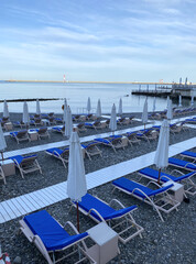 Sun beds and umbrellas on the first line of the sea. Hotel beach.