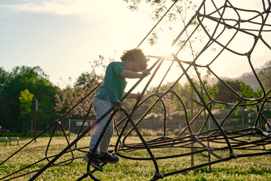 Child climbing on a Rope-ladder web in a playground.
