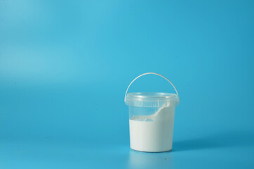 Bucket with white paint on a blue background.