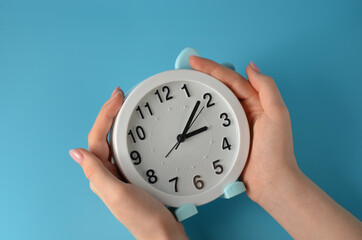 Clock in hands on a blue background.