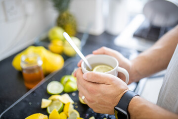 Male hands holding a cup of lemon tea above lime slices