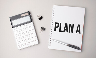 The word plan a is written on a white background next to a pen ,calculator and reports. Business concept