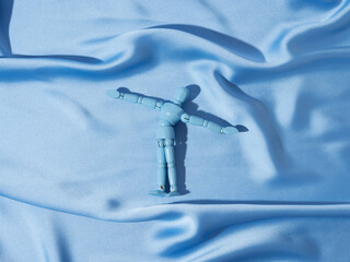Puppet on blue satin texture background as man swimming in ocean sea concept