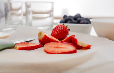 Chef's knife and slices of strawberries on a cutting board. Baking paper. Healthy food concept.