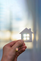 House in hand, in the rays of the sun. Property protection concept. Place for text