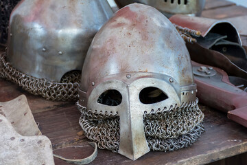 an old knight's helmet with scratches and dents lies on a wooden table.