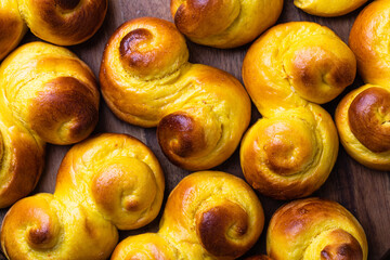 Swedish traditional christmas bun Lussekatter or Lussebullar on a rustic wooden table background