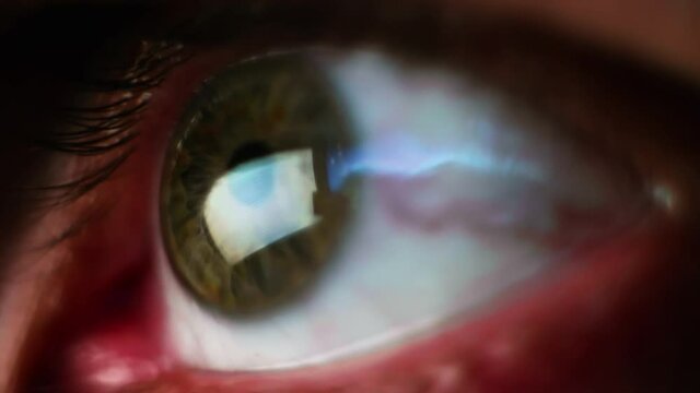 Macro view. Man's eye with reflectio of news from screen that man reads and scrolls.