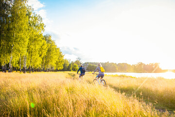 beautiful field at sunset, couple riding bikes in the distance