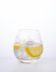 Glass with lemon mineral water and splashes on a white background. Front view and copy space