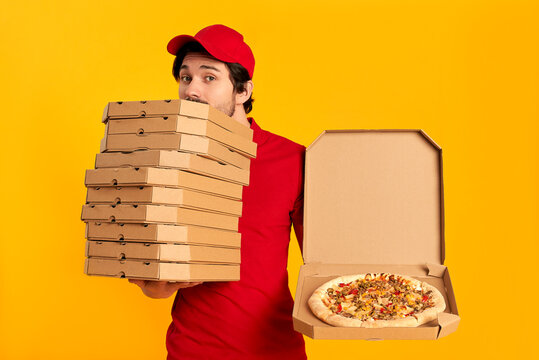Young bearded delivery man with boxes of pizza isolated on orange background. Home delivery.