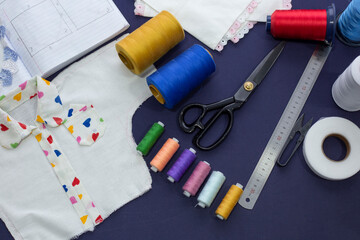 Sewing tools: cloth, scissors, pins, tape measure on blue background